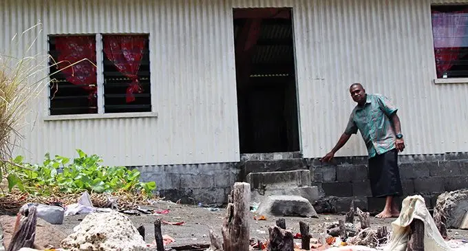 Nasau Village headman Ionisio Navosese shows the depth of the seawater when the tide rises. The foreground shows the remains of a house foundation. Photo: Kelera Sovasiga