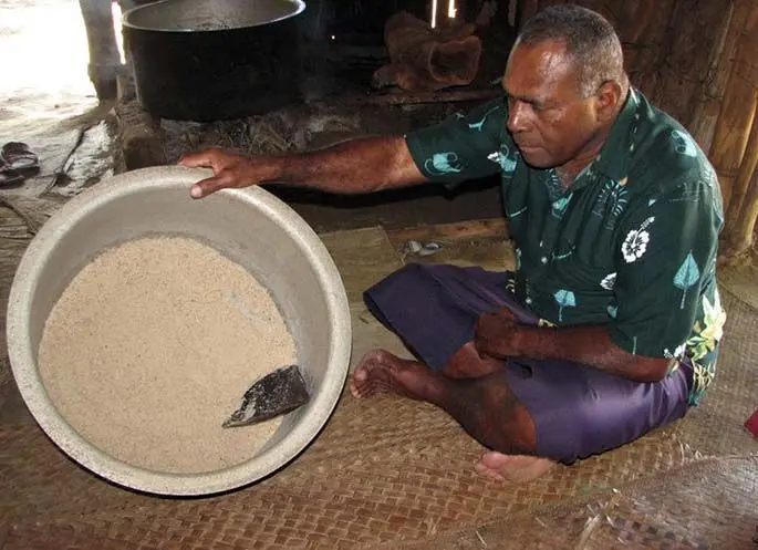 A Lomawai villager showing the salt that was traditionally collected in the pot.