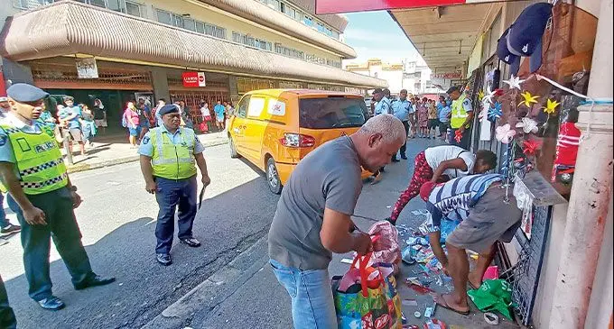 Anthony Balagilala (right) clears items after the Nina Street accident. Photo: Ronald Kumar 