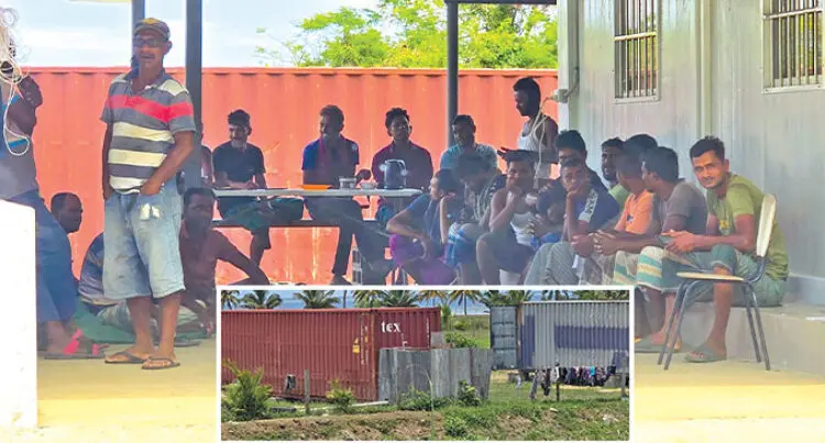 A photograph of several Bangladeshi men in Fiji sat or stood around a table.