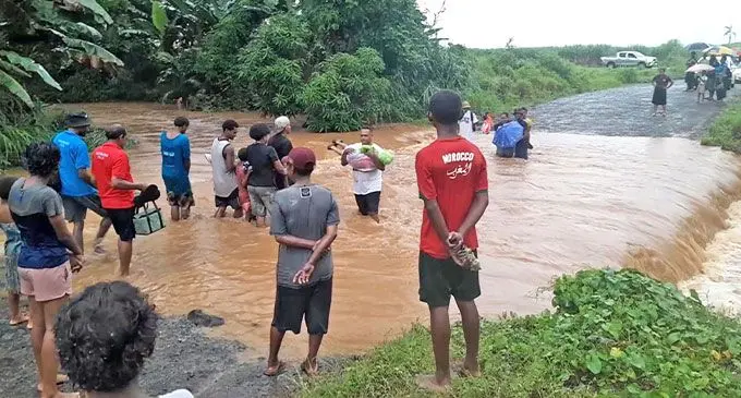 Parents carrying their children across the flooded Maururu crossing in Ba on January 31, 2025.