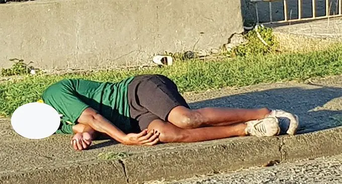 An intoxicated individual sleeping on a sidewalk.