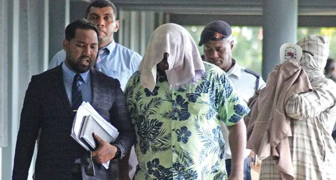 From Left: Defence lawyer John Prasad talking to his clients, Mohammed Aiyaz and Mohammed Sameer (fully covered) escorted by police at the Labasa Magistrate’s Court, Labasa, on May 22, 2024. Photo: Shratika Naidu