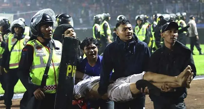 Fans carry an injured man following clashes during a football match at Kanjuruhan Stadium in Malang, East Java, Indonesia. Photo: Yudha Prabowo/AP