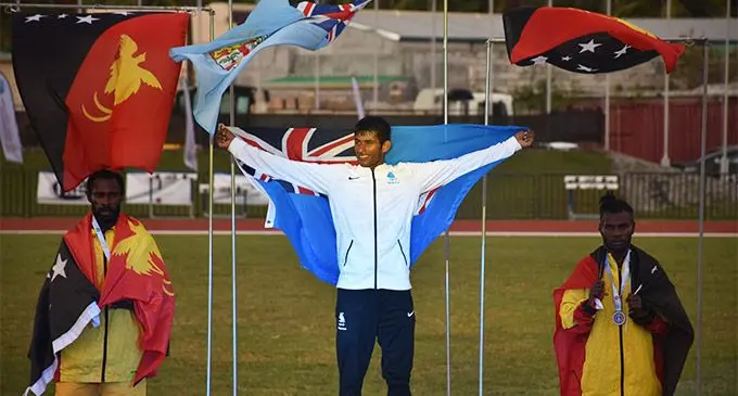 Yeshnil Karan flies the Fiji flag on the medal podium of the Pacific Mini Games in Saipan on June 24, 2022. Karan won the gold medal in the men’s 1500m final. Photo: Athletics Fiji  