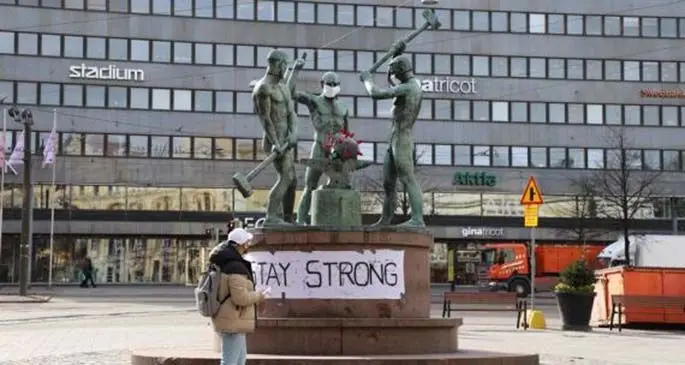 A citizen stops at the famous city sculpture "Three Smiths" which has been put on facial masks, in Helsinki, Finland, March 31, 2020. (Xinhua/Zhu Haochen)