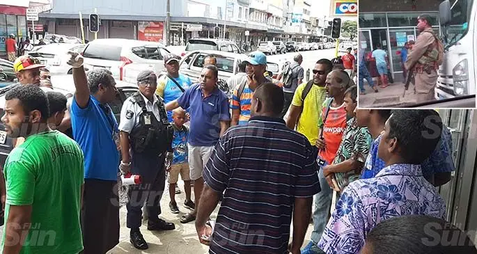 A staff member of Fiji National Provident Fund’s Lautoka branch talks to customers on March 30, 2020. Photo: Salote Qalubau. Inset: A Republic of the Fiji Military Forces soldier stands guard outside the Fiji National Provident Fund Lautoka branch on March 30, 2020.