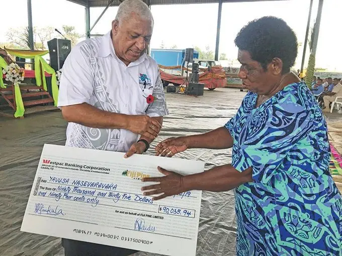 A member of the Yavusa Nasevaravara receiving her checeque from the Prime Minister Voreqe Bainimarama at Tropik Wood  yesterday.  Photo: Charles Chambers