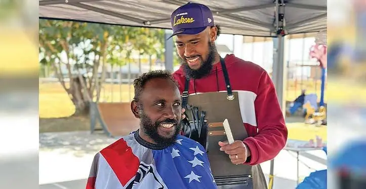 Barber, Enele Ma’afu with a customer.