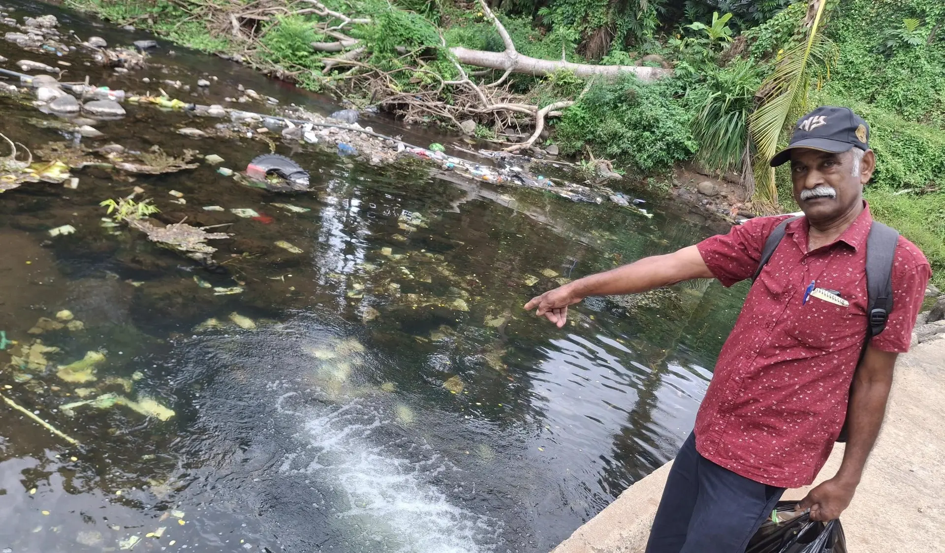 Sant Lal pointing to the rubbish and the ID cards thrown in the river. Photo: Mereleki Nai  