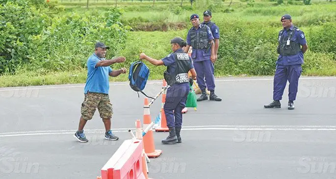 Sakeo Celekilagi (wearing blue) receives his bags from his family at the Sawani border after been stuck outside of the confined area. Photo: Kelera Sovasiga