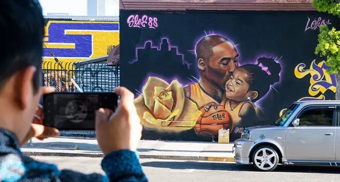 A man photographs a mural honoring NBA star Kobe Bryant and his daughter, who died in a helicopter crash, in Los Angeles, the United States, Feb. 16, 2020. (Xinhua/Qian Weizhong)
