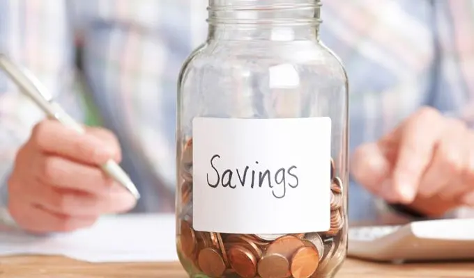 Woman Calculating Budget With Savings Jar In Foreground