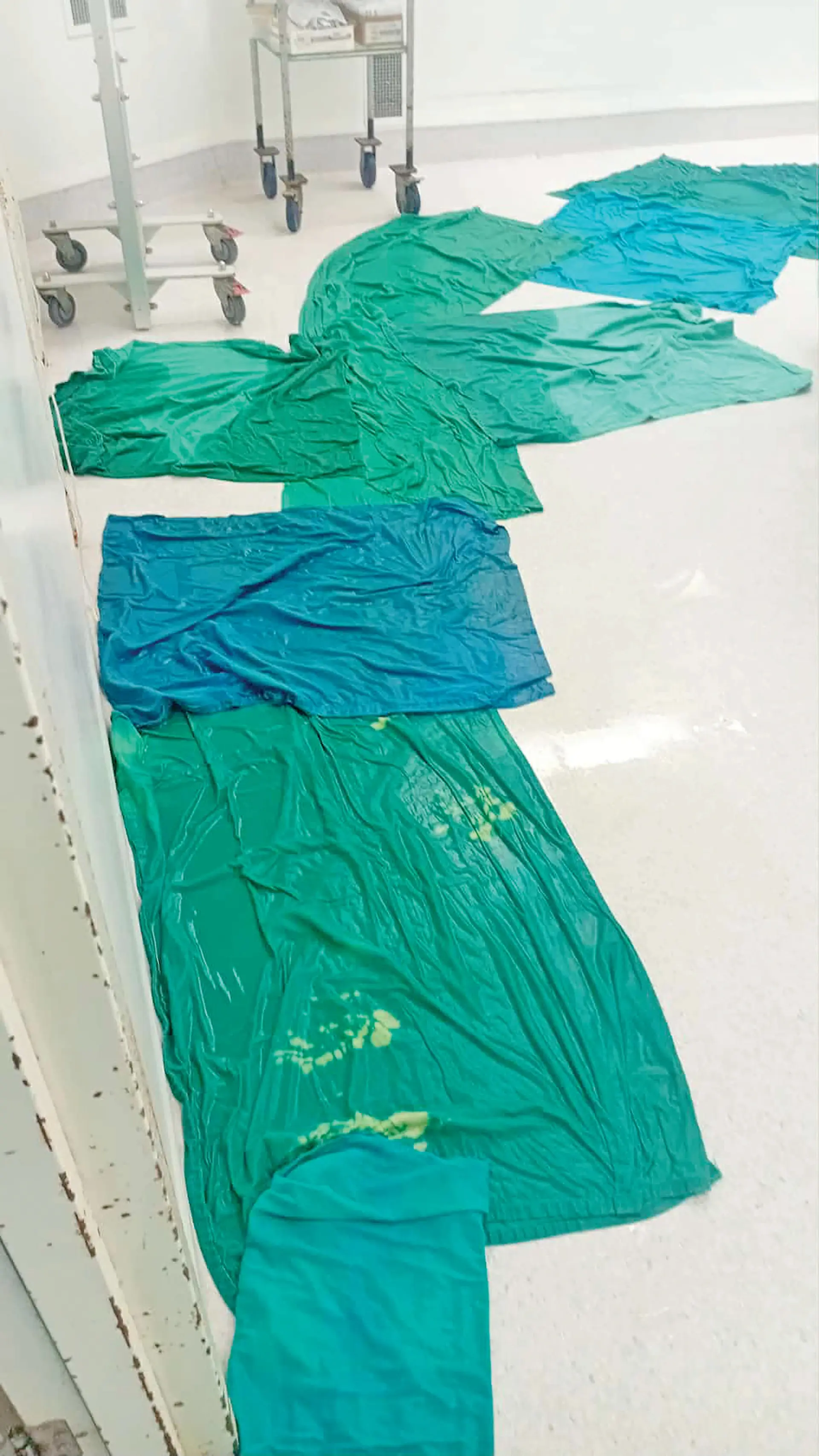 damp hospital linens hung to dry over blocked drains, sinks filled with murky water.