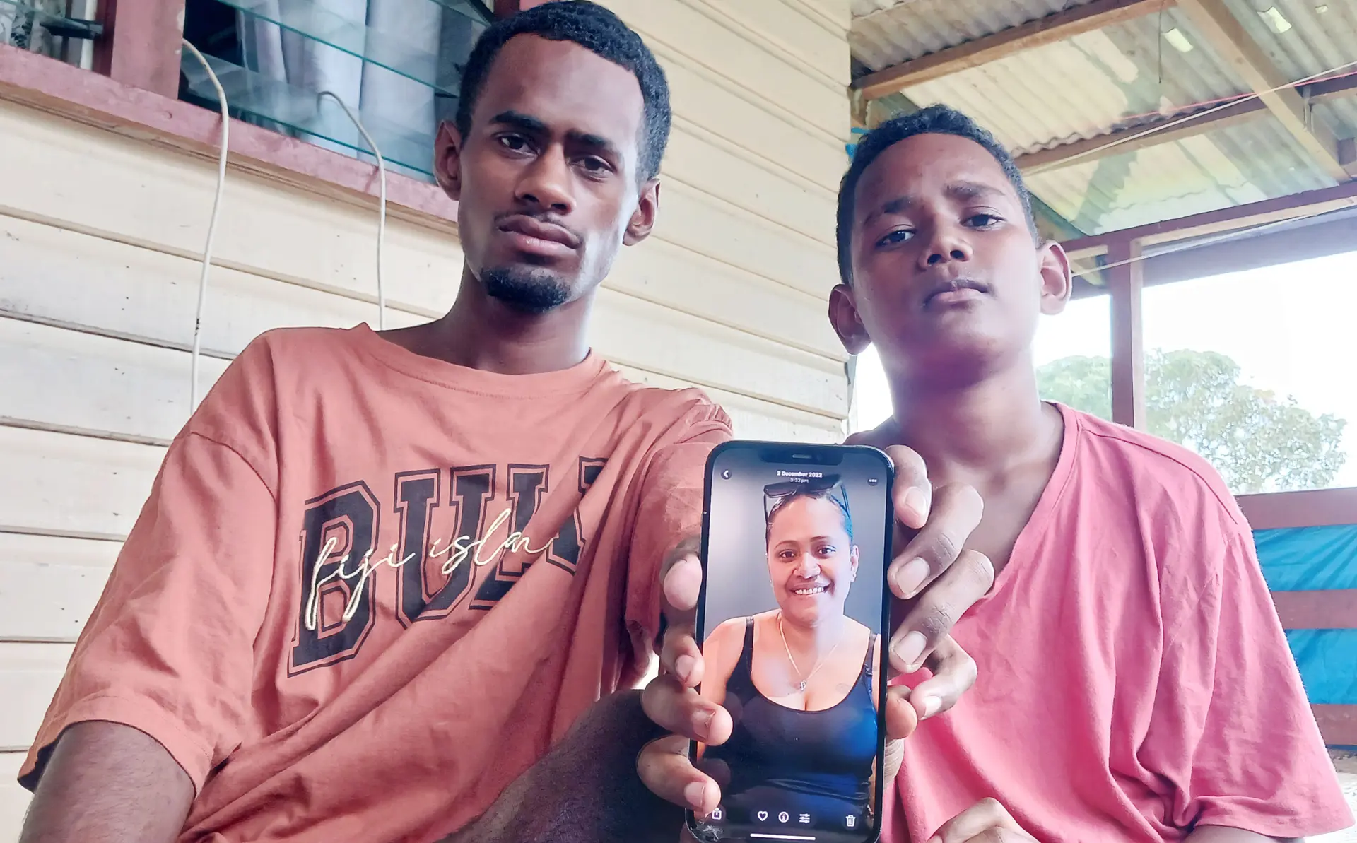 Brothers Joshua Immanuel Waqavuki, 17, and Rupeni Waqavuki, 12, with a photograph of their late mother, Anaseini Waqavuki, who was killed in Australia.