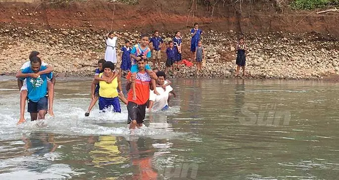 Lawaki Settlement residents demonstrate how they would help their children cross the Korotari River on a daily basis. Photo: Renu Radhika