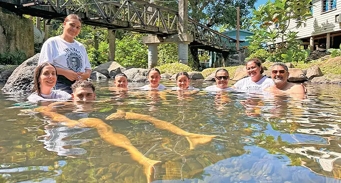 A photo of the Traill family swimming together in a natural pool.