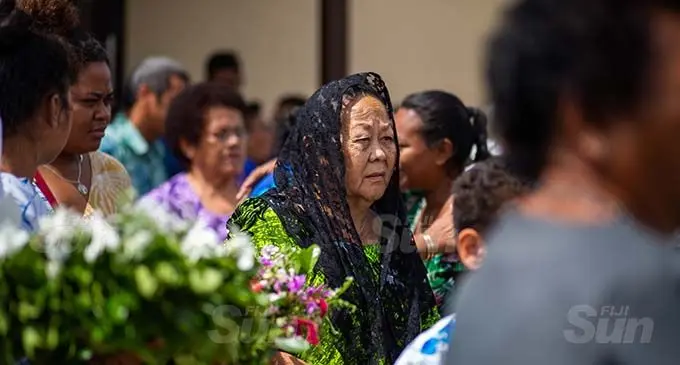 Rosie Chute, widow of the late businessman Patrick Chute, follows her husband’s casket out of St Joseph The Worker parish in Samabula, yesterday. Photo: Leon Lord