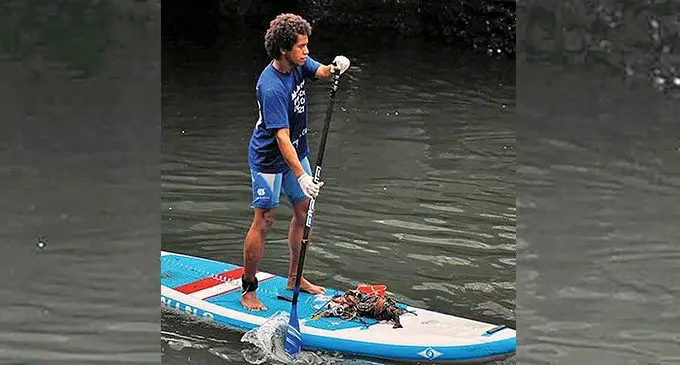 Epeli Lalagavesi collecting rubbish on his Stand-up paddle board.  
