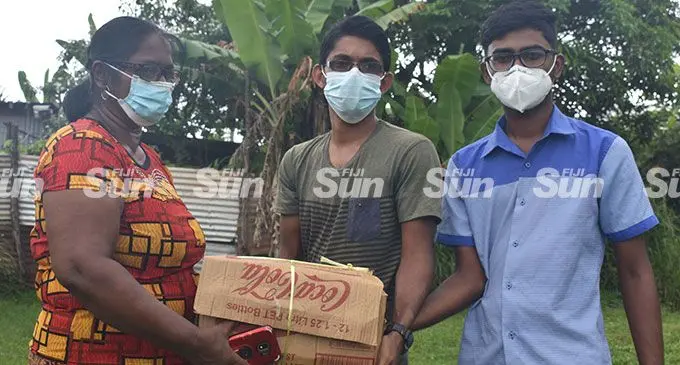 Krishna Kanti receives a box of grocery from the One Nation Our People Youth Club members, Suleman Ali and Soheb Ali at Votualevu in Nadi. Photo: Mereleki Nai