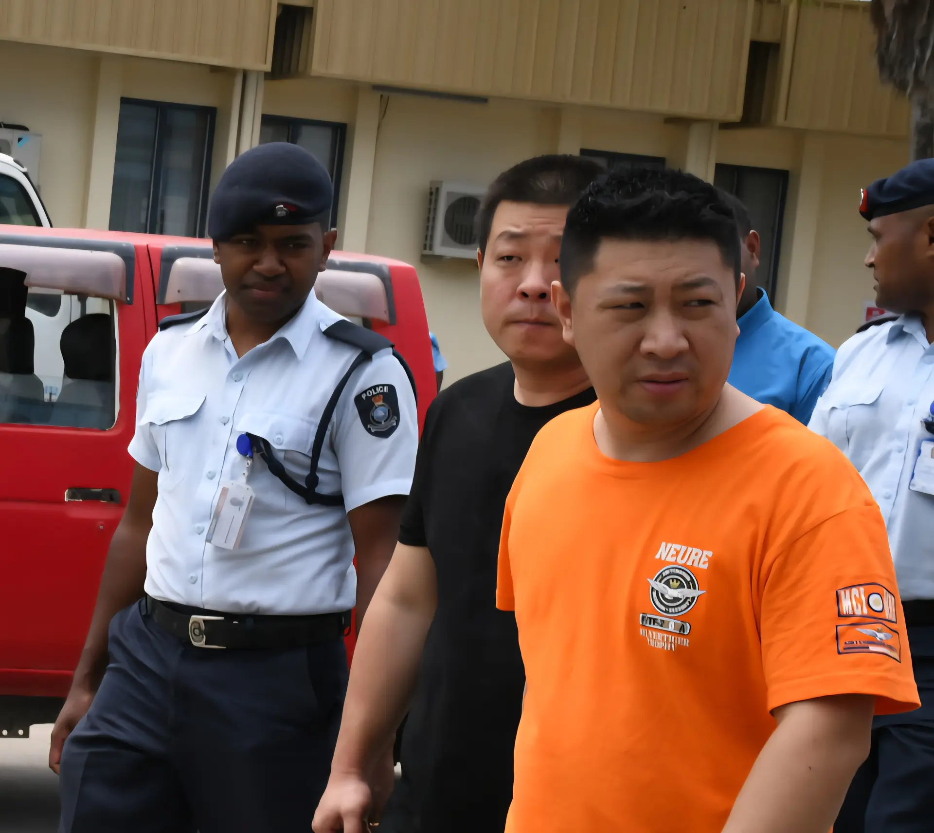 Xu Qiang (wearing orange t-shirt) and Wang An with police officers at the Nadi Magistrate Court.