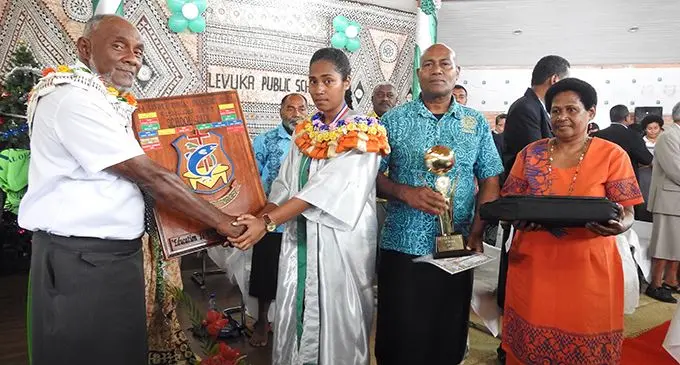Chief guest Suliasi Tawake (left) hands over the Dux Shield to Salanieta Likucevuga.   Her father Peceli Maisuva is on the right.  Photo: Manhar Vithal
