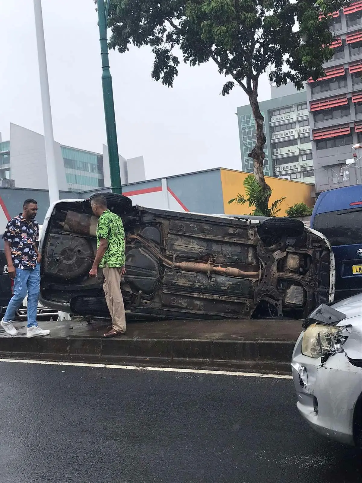 A vehicle lies on its side following a road accident along Stinson Parade in Suva during wet weather conditions this morning, as a man stands nearby assessing the scene.