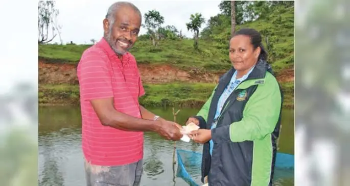 Joseva Madraitabua receives payment for tilapia sales from Fisheries Officer, Makelesi Danford at his farm in Lokuya, Tailevu. Photo: Ministry of Fisheries