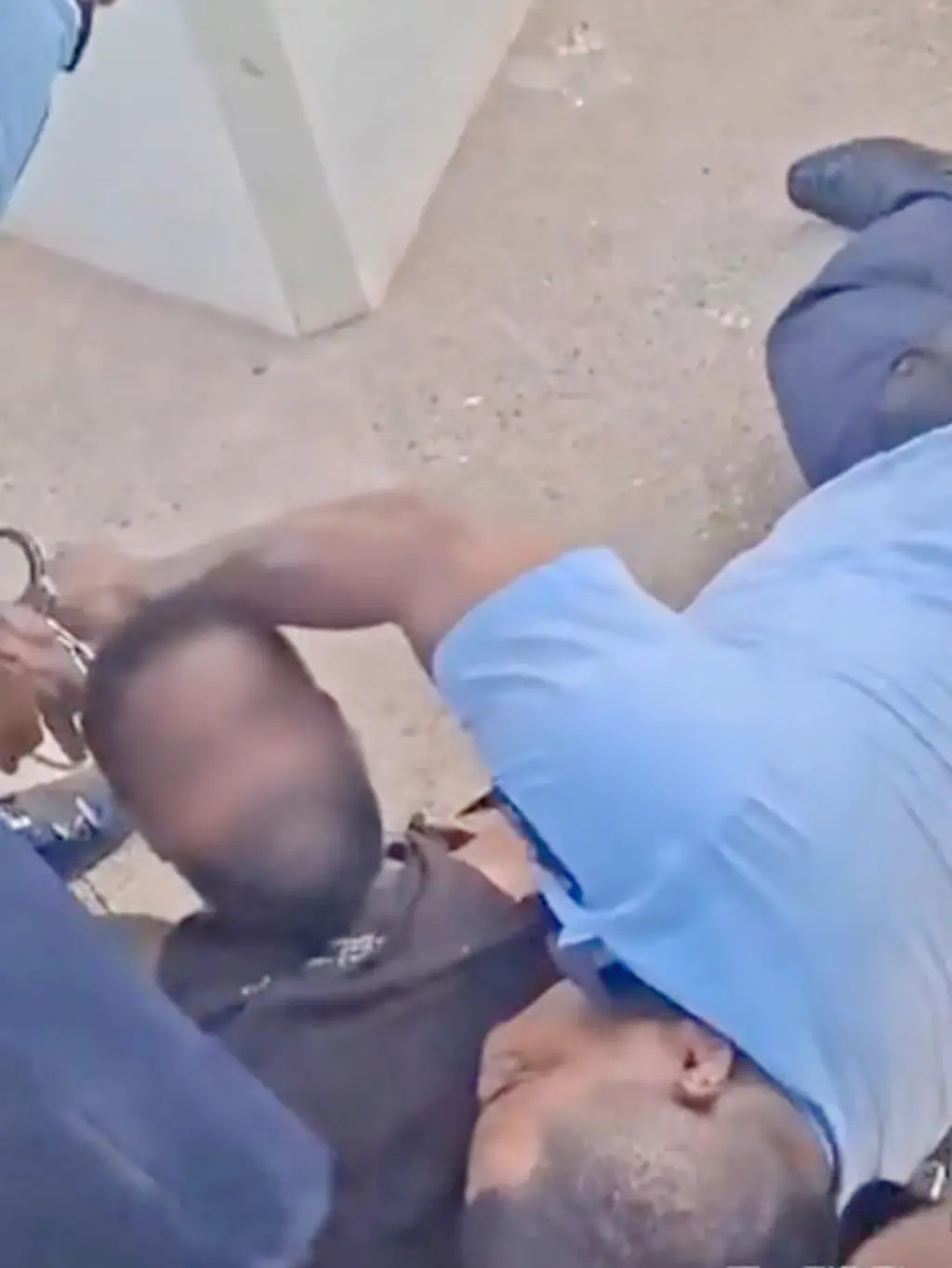 A still from video footage showing police officers attempting to restrain a suspect.