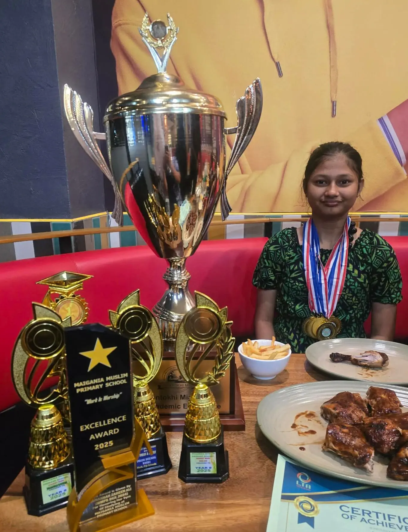 Maigania Muslim Primary School Dux, Zahra Zuhairaa, with her awards and medals, having a treat to celebrate her achievement after graduation. 