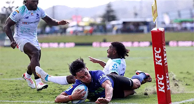Blues fullback Zarn Sullivan dives over to score the first of his two tries despite a tackle attempt from Isikeli Rabitu today. Photo: Newshub 
