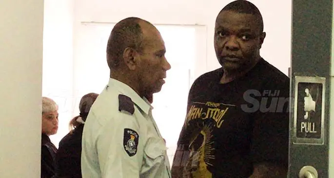 Kiala Henri Lusaka, left, is escorted by a Police officer. Photo: Ashna Kumar