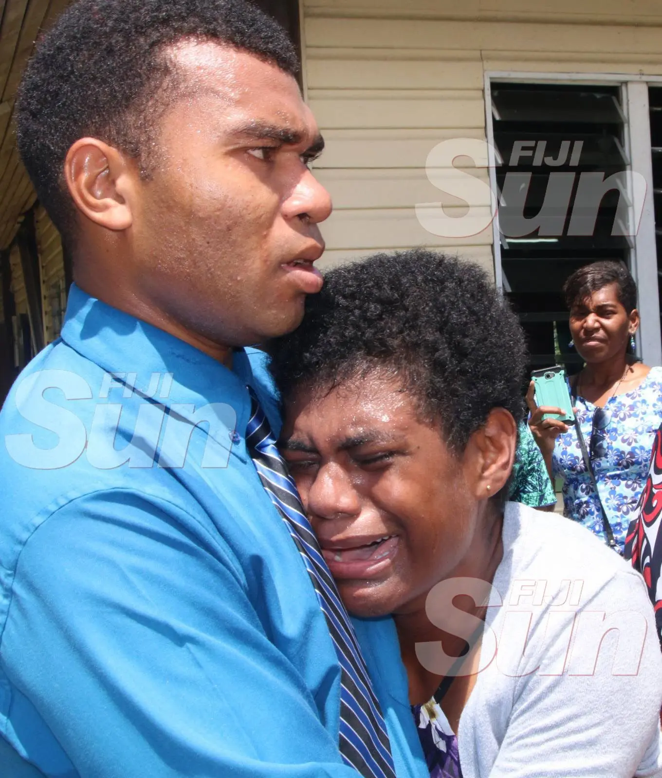 Cathrine Baleinagaga is comforted by a comrade at the arrival of the body of the late Police Constable Siuta Niumataiwalu .