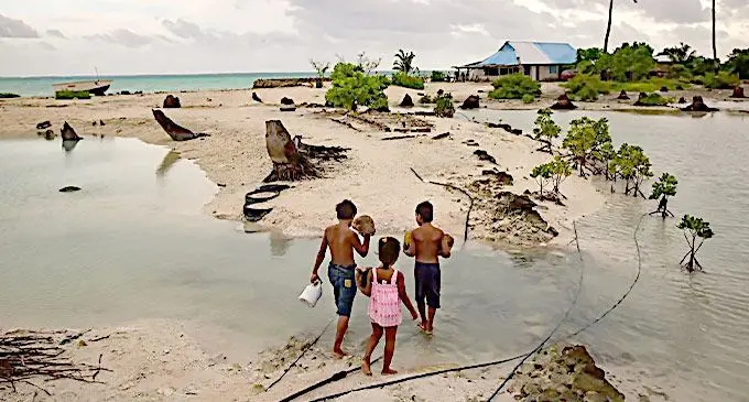 Residents of a village in South Tarawa waded through water during high tides that flooded the region, leaving homes isolated until the waters receded.Photo: Josh Haner / The New York Times