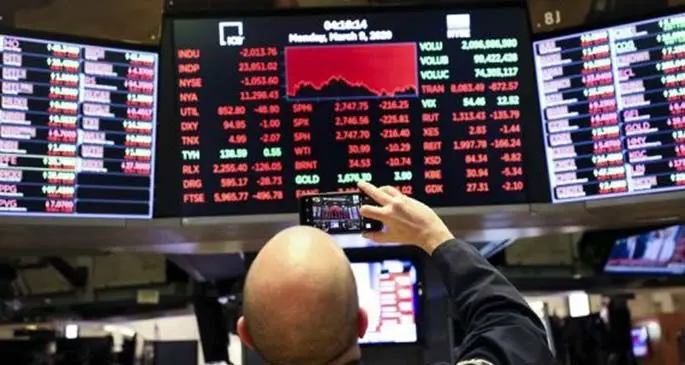 A trader shoots the closing numbers on screens by cellphone at the New York Stock Exchange (NYSE) in New York, the United States, March 9, 2020. (Xinhua/Wang Ying)