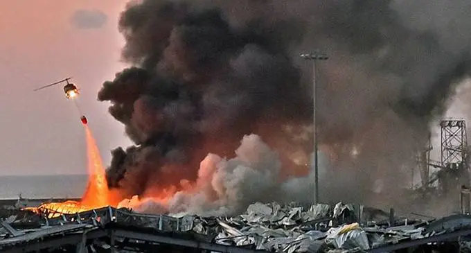 A helicopter tries to douse a fire at the scene of the explosion in the port of Beirut