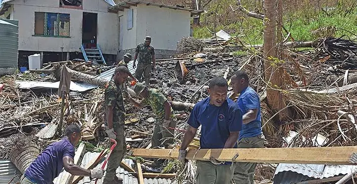 Members of the Republic of Fiji Military Forces cleaning up wreckage from Cyclone Yasa in 2021.