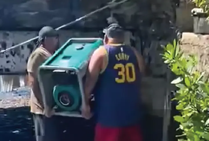 Three men were forced to lift a heavy portable generator up a concrete wharf ledge.