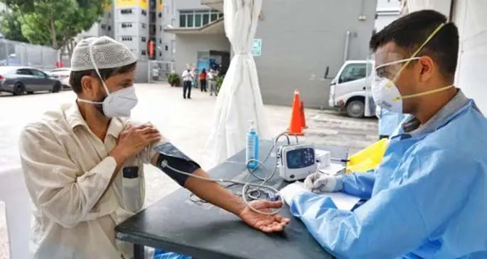 A foreign worker (L) gets medical check near the Toh Guan Dormitory in Singapore on April 8, 2020. (Ministry of Manpower Singapore/Handout via Xinhua)