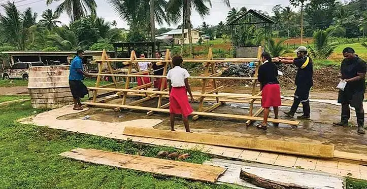 Year 13 Agriculture students help built a wooden structure to plant vegetables on.