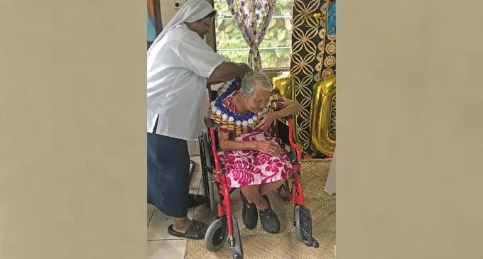 Sister Mere Lauaki garlands Mary Fong during her 100th birthday celebration.  