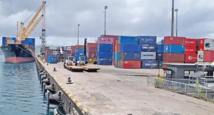 A photograph of a cargo ship in the water next to shipping crates at the Fiji Ports Terminal Limited in Suva.
