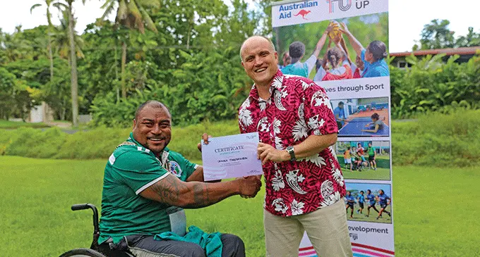 Australian Charge d’Affairs John Williiams presents a certificate of participation to Smash Down Barriers development officer Iokabe