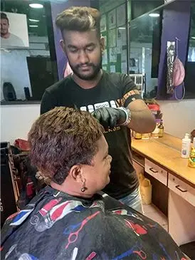Rishneet Chand serving a customer at his salon in Makoi.