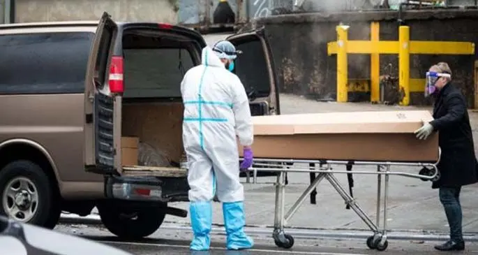 A hospital worker in personal protective equipment (PPE) helps a funeral home worker wheel the body of a deceased person into a van outside Brooklyn Hospital Center in the Brooklyn borough of New York, the United States, on April 24, 2020. (Photo by Michael Nagle/Xinhua)