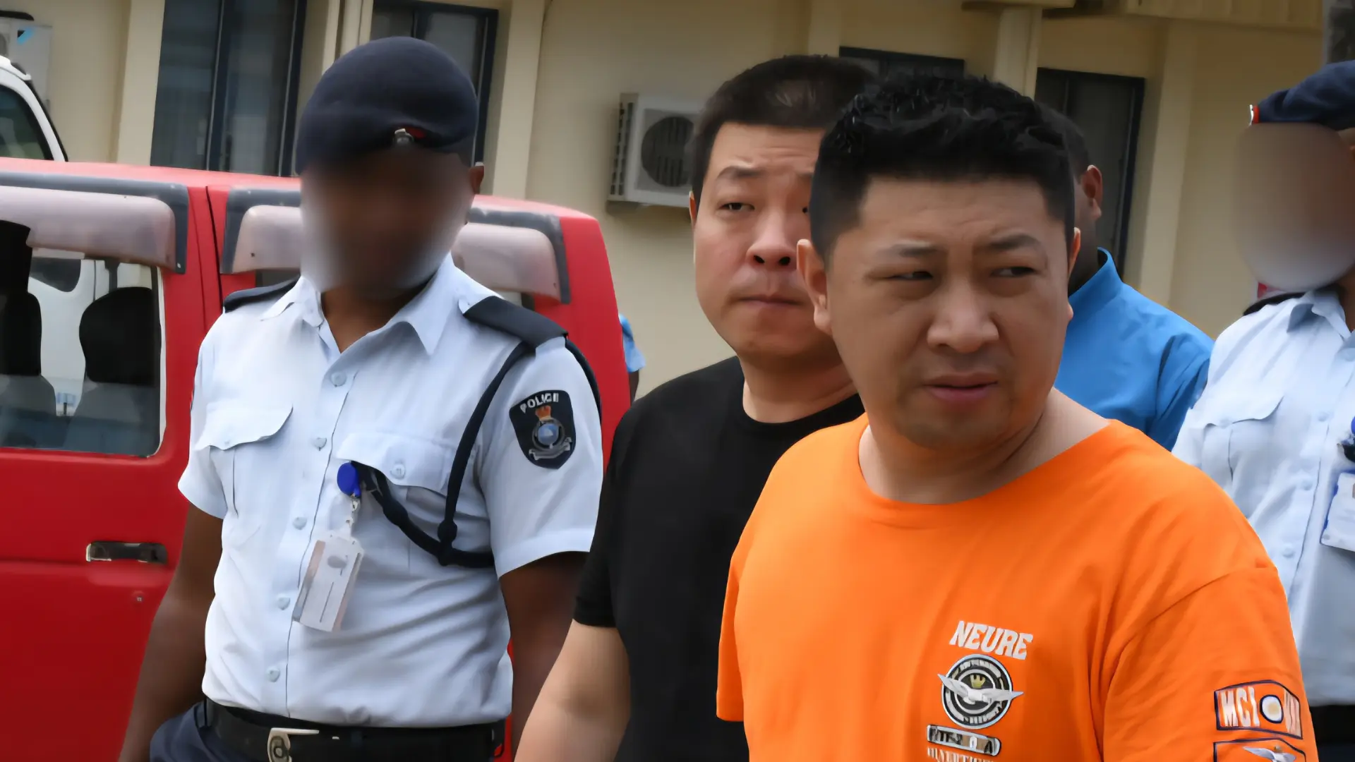 Xu Qiang (in orange T-shirt) and Wang An (in black T-shirt) with police officers at the Nadi Magistrate Court. 