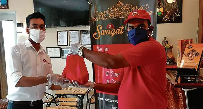 Fiji Eats staff member Mohammed Faheem (right) makes a delivery to a customer.  Photo: Fiji Eats