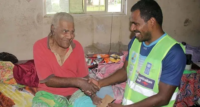 Josefa Sema, a man living with disability, receives his cash assistance at his home.