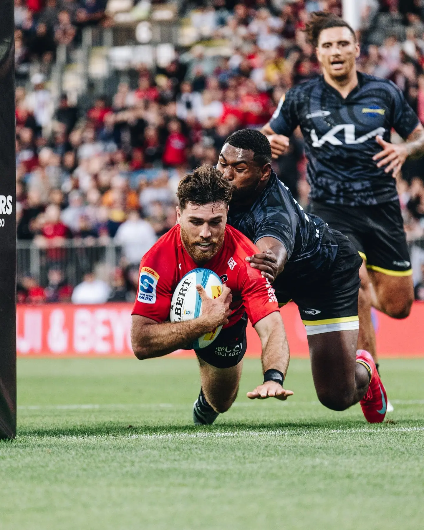 Kyle Preston dives over to score a try for Crusaders despite a tackle from Hurricanes winger Kini Naholo in Christchurch on February 14, 2025. Photo: Crusaders