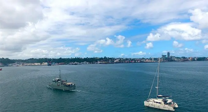 A Fiji Navy boat assists a troubled catamaran back to  Suva habor.